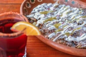 Sope de bistec with cream beside a red drink at Las Guacamayas