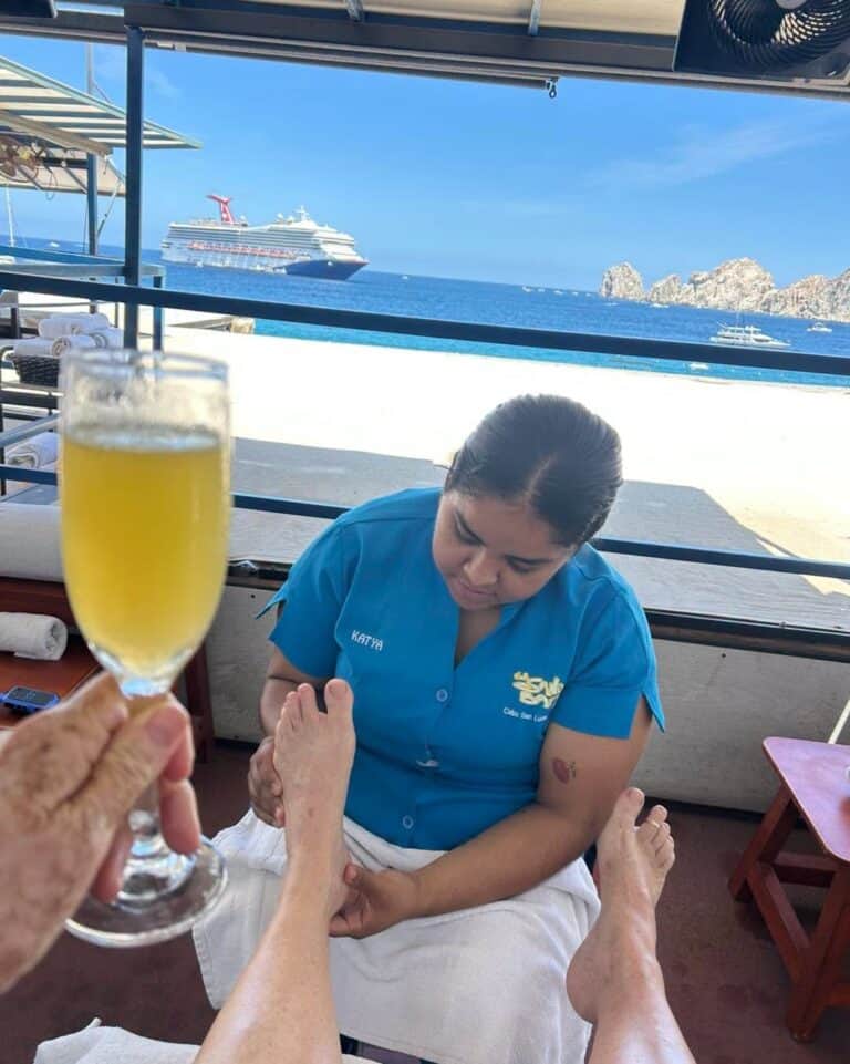 Therapist giving a foot massage while the guest holds a mimosa, with the Arch in the distance