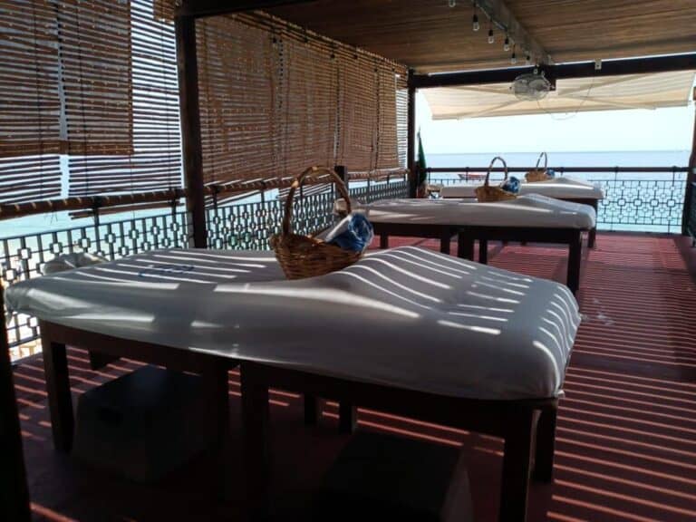 Row of massage tables with towel baskets under the shade of the open-air deck