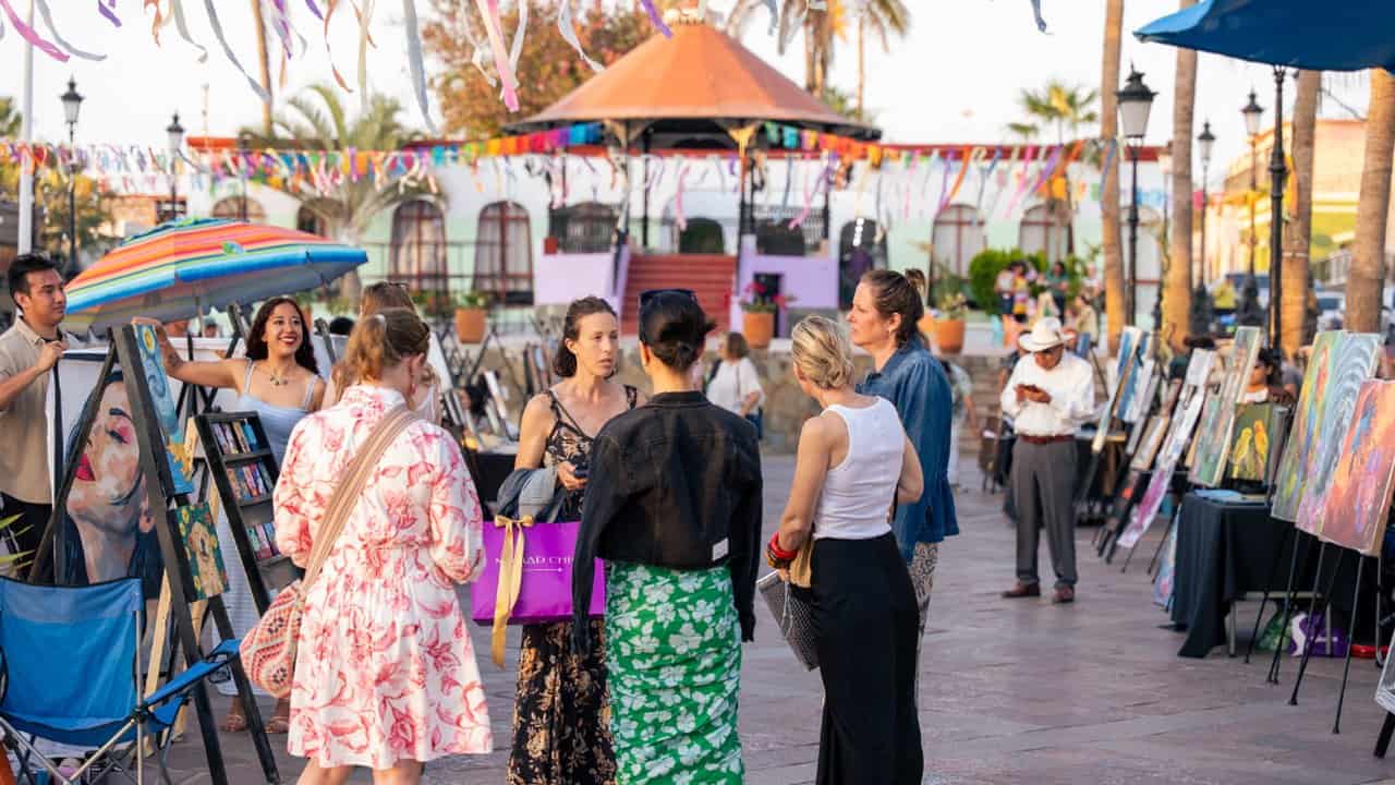 Outdoor art fair in a plaza with papel picado, from the official ABC Art Baja California site