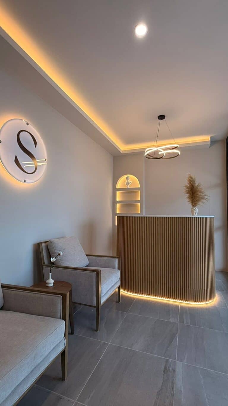 Waiting area at Sorelle Skin Care Studio with two armchairs, the lit S logo and the reception desk