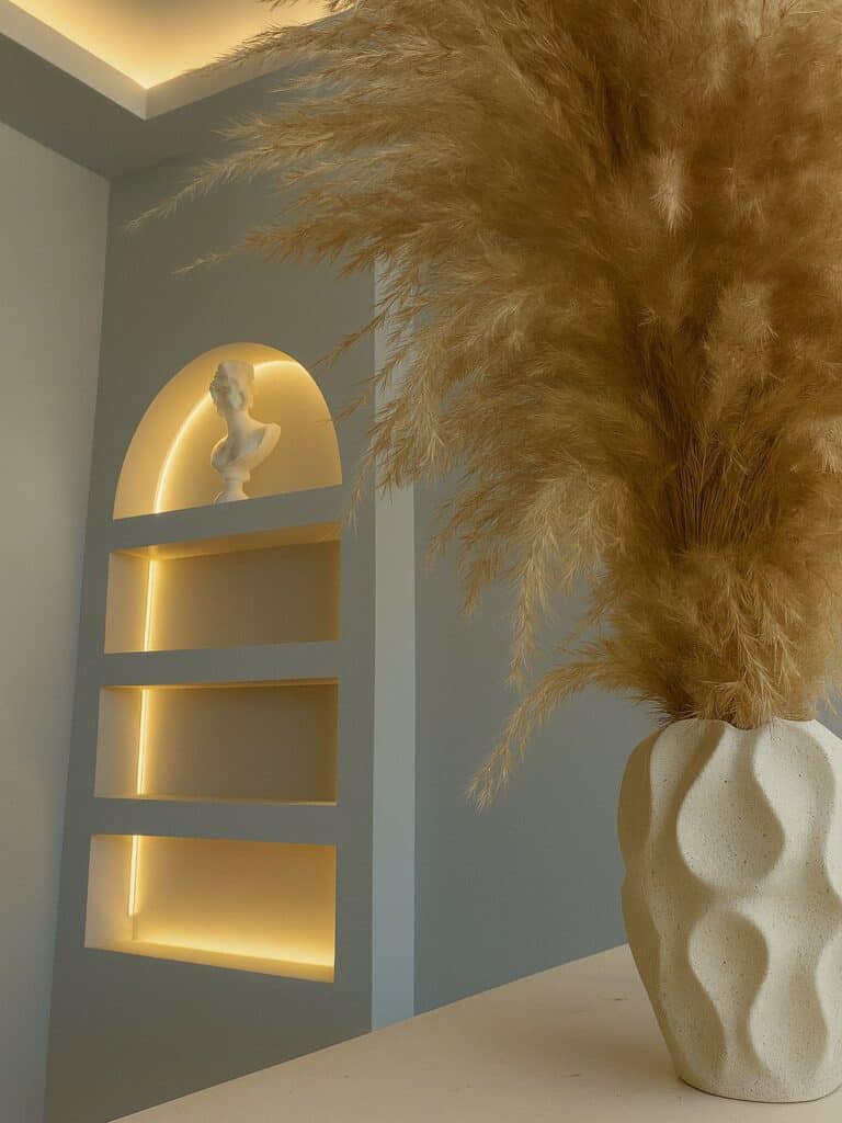 Lit arched niche with a classical bust and pampas grass in the Sorelle reception area