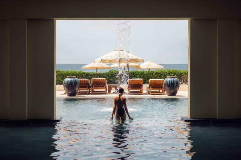 Guest wading into the spa pool toward loungers and the ocean at Waldorf Astoria Spa