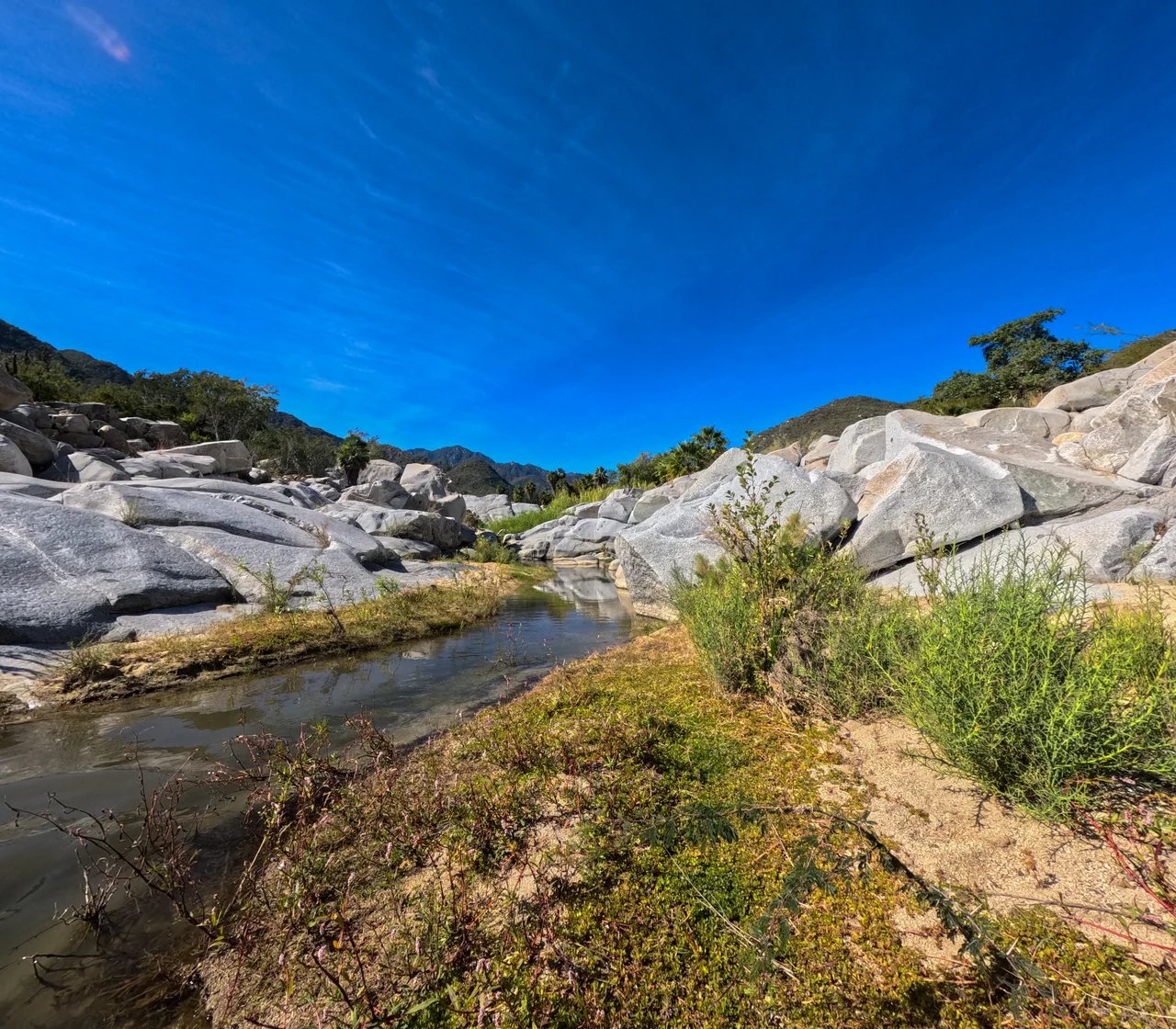 Clear stream winding between white granite boulders at Rancho Ecológico El Refugio, in the Sierra de la Laguna — photo by Adrián De Antoni
