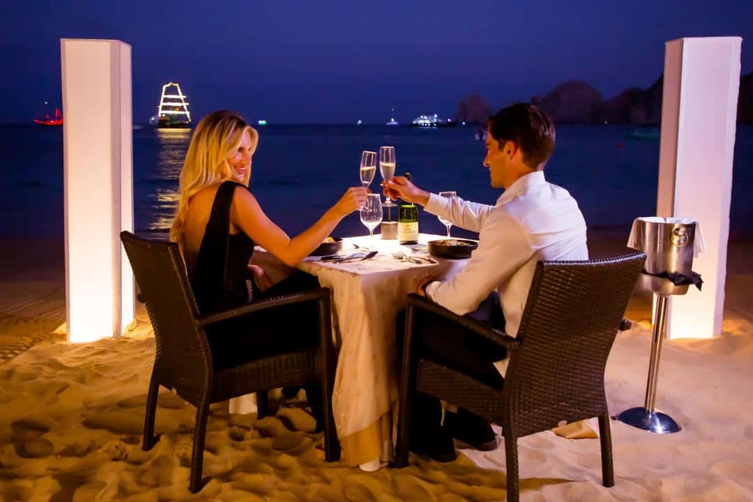 A couple toasting during a candlelit dinner on Médano Beach.